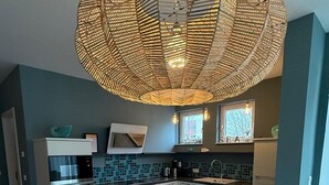 A modern kitchen with a wooden dining table, grey chairs, and a hanging light fixture. - Where Design Meets Coziness—High-Quality Vacation Rental 5 Minutes from the Beach, 3 Beds (Karlshagen)