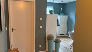 A hallway with a white door, a small wooden stool, a woven basket, and two tall blue vases with spherical objects. - Where Design Meets Coziness—High-Quality Vacation Rental 5 Minutes from the Beach, 3 Beds (Karlshagen)