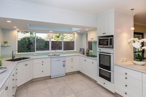 A modern kitchen with white cabinetry, a dishwasher, an oven, and a microwave.