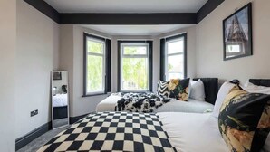 Una camera d'albergo con una coperta a quadri, un'ampia finestra vista e un quadro appeso al muro.