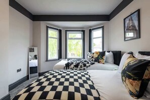 Ein Hotelzimmer mit karierter Bettdecke, einem großen Fenster mit Aussicht und einem Bild an der Wand.