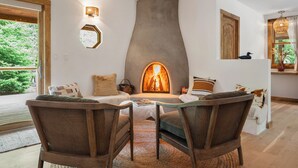 Uma sala de estar aconchegante com lareira, móveis de vime e vista para o verde lá fora.