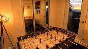A foosball table in a room with a door leading to a balcony. - 564 C | Le Refuge Spa Riviere & Billard (Saint-Léon-de-Standon)