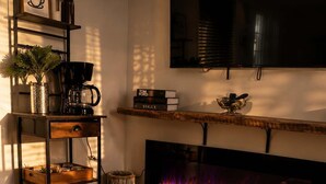 A modern living room with a fireplace, wooden furniture, and a coffee machine. - 564 C | Le Refuge Spa Riviere & Billard (Saint-Léon-de-Standon)