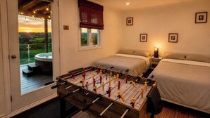 A room with a foosball table, two beds, a window with a view, and a small table with a lamp. - 564 C | Le Refuge Spa Riviere & Billard (Saint-Léon-de-Standon)