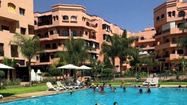 A swimming pool surrounded by multi-story buildings with balconies. - Nice Property Marrakech Village With Pools and Gardens (Marrakech)