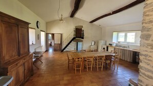 Une cuisine spacieuse avec un coin repas, des meubles en bois et un mur en pierre.