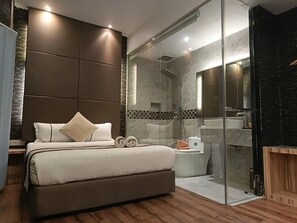 A modern bedroom with a large bed, a glass shower enclosure, and a separate bathroom with a bathtub. - Herehotel.com (Johor Bahru)