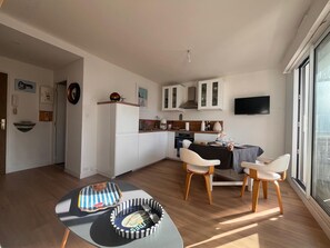 Eine moderne Küche mit weißen Schränken, einem Essbereich mit Tisch und Stühlen sowie einem großen Fenster, das für natürliches Licht sorgt.