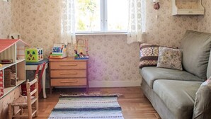A child's playroom with a wooden desk, colorful toys, a green sofa, and a patterned rug. - 4 Person Holiday Home in Ronneby (Listerby)