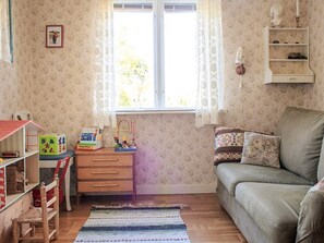 A child's playroom with a wooden desk, colorful toys, a green sofa, and a patterned rug. - 4 Person Holiday Home in Ronneby (Listerby)