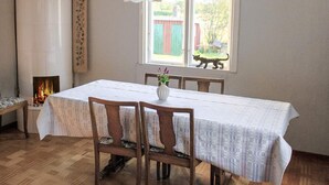 A dining room with a table set for four, a fireplace, a window with a view, and a hanging light fixture. - 4 Person Holiday Home in Ronneby (Listerby)