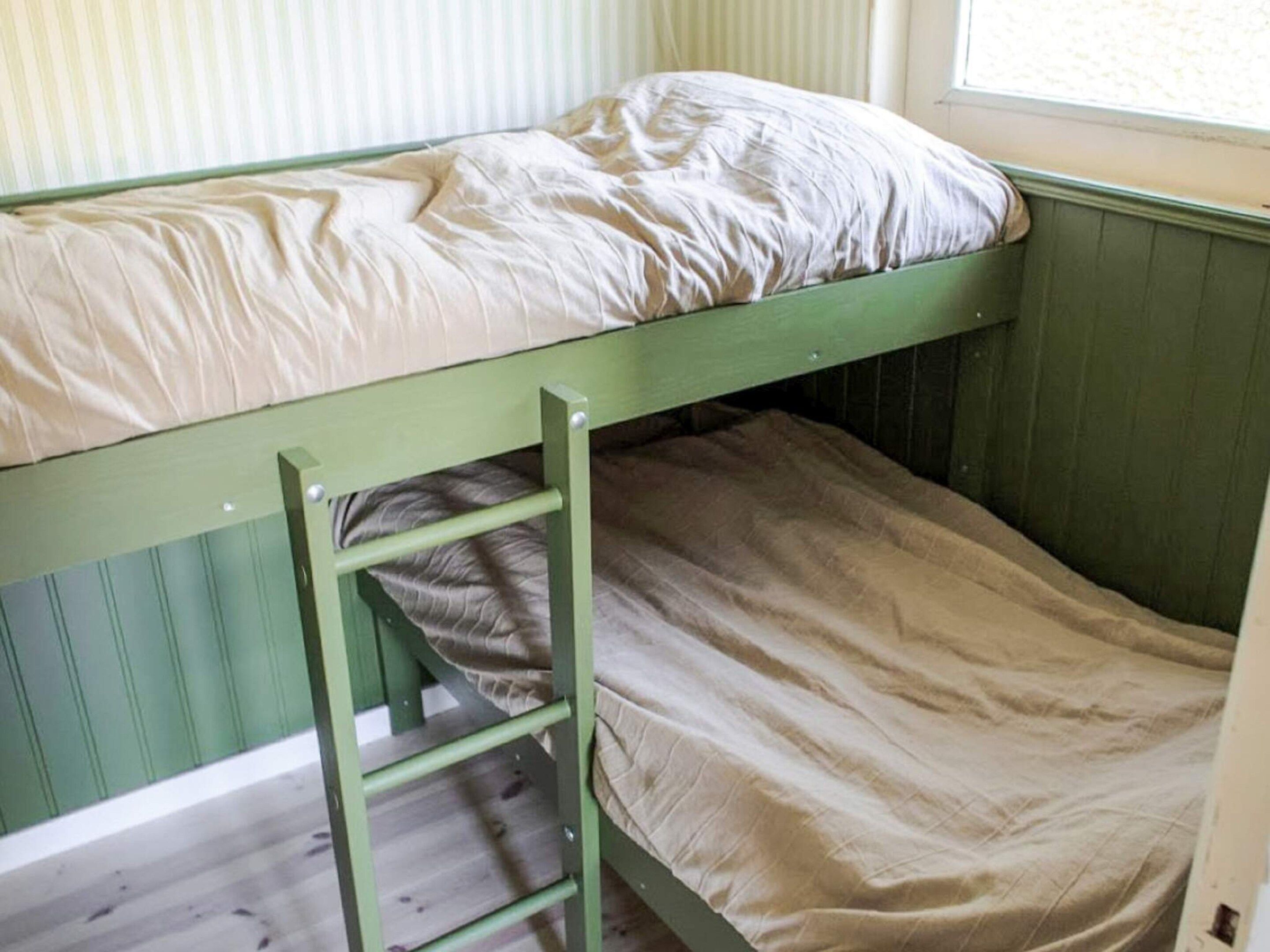 Un lit superposé avec une échelle, une fenêtre et un mur à rayures.