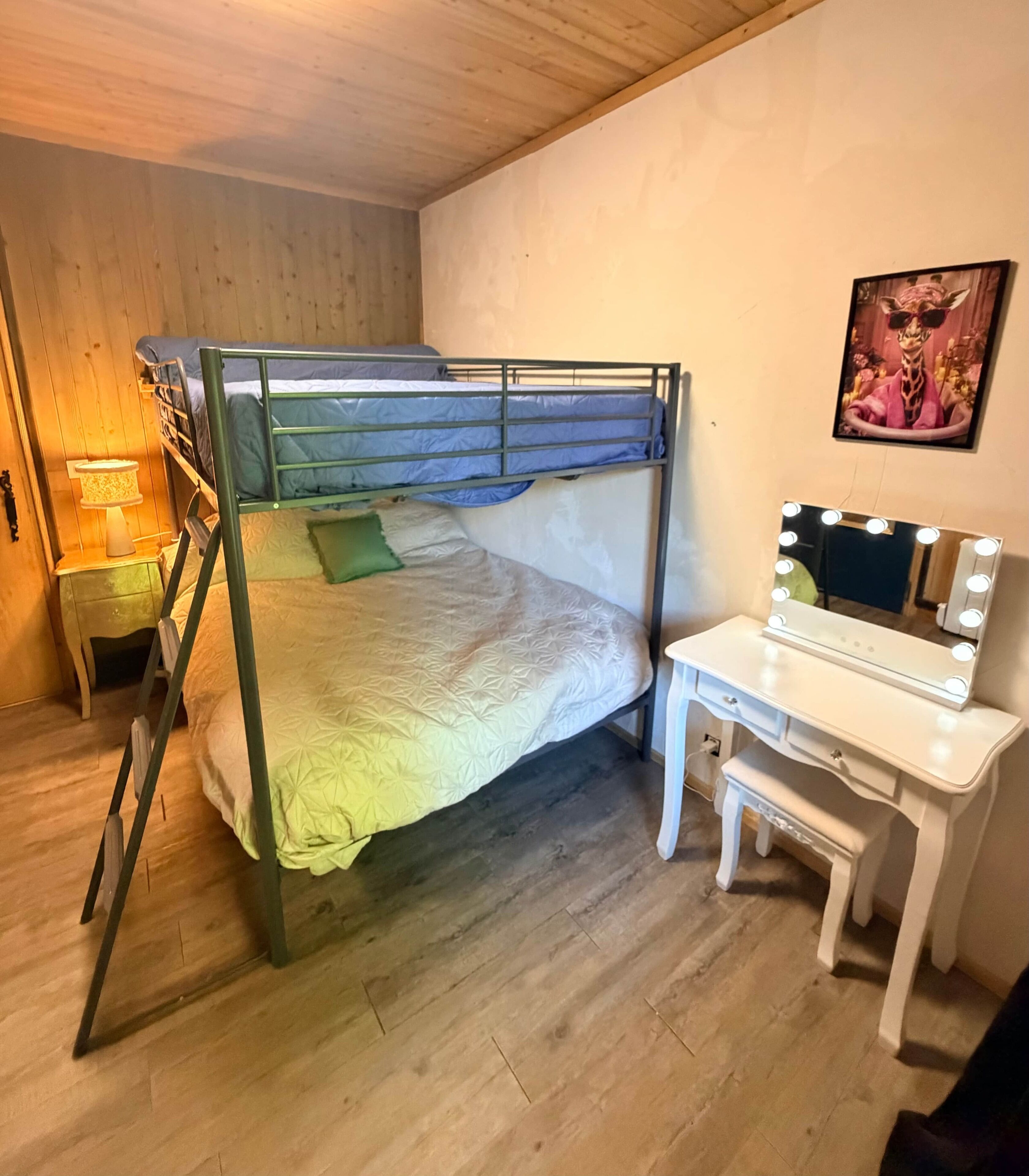 A bunk bed with a desk and chair, a lamp, and a framed picture on the wall.