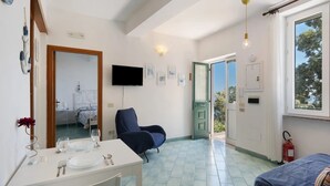 Una habitación con mesa de comedor, una silla, una cama, televisor y ventana con vistas.