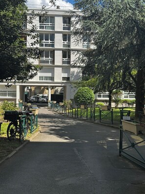 Um edifício de vários andares com entrada coberta, suporte para bicicletas e um caminho que leva à entrada.