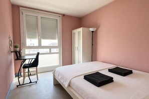 Quarto com cama, escrivaninha, cadeira, guarda-roupa e janela com persianas.