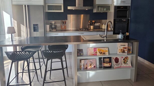Una cucina moderna con elettrodomestici in acciaio inox, un'isola centrale con sgabelli da bar e una mensola con libri di cucina.