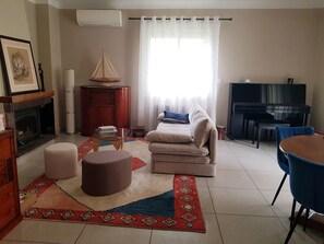 Un salon comprenant un canapé, un pouf, une table basse en verre et une cheminée.