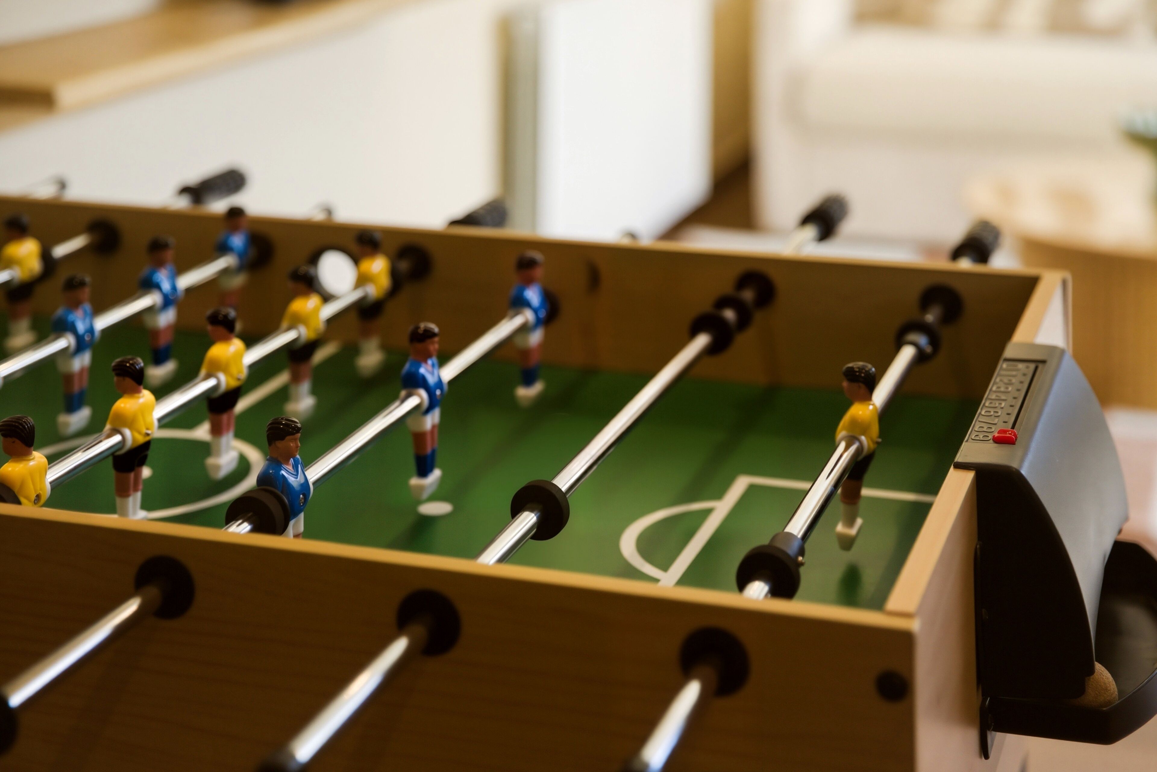 Een tafelvoetbaltafel met poppetjes in blauwe en gele uniformen.