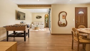 Ein Wohnzimmer mit Kicker, einer Couch, einem Esstisch mit Stühlen und einem Spiegel an der Wand.