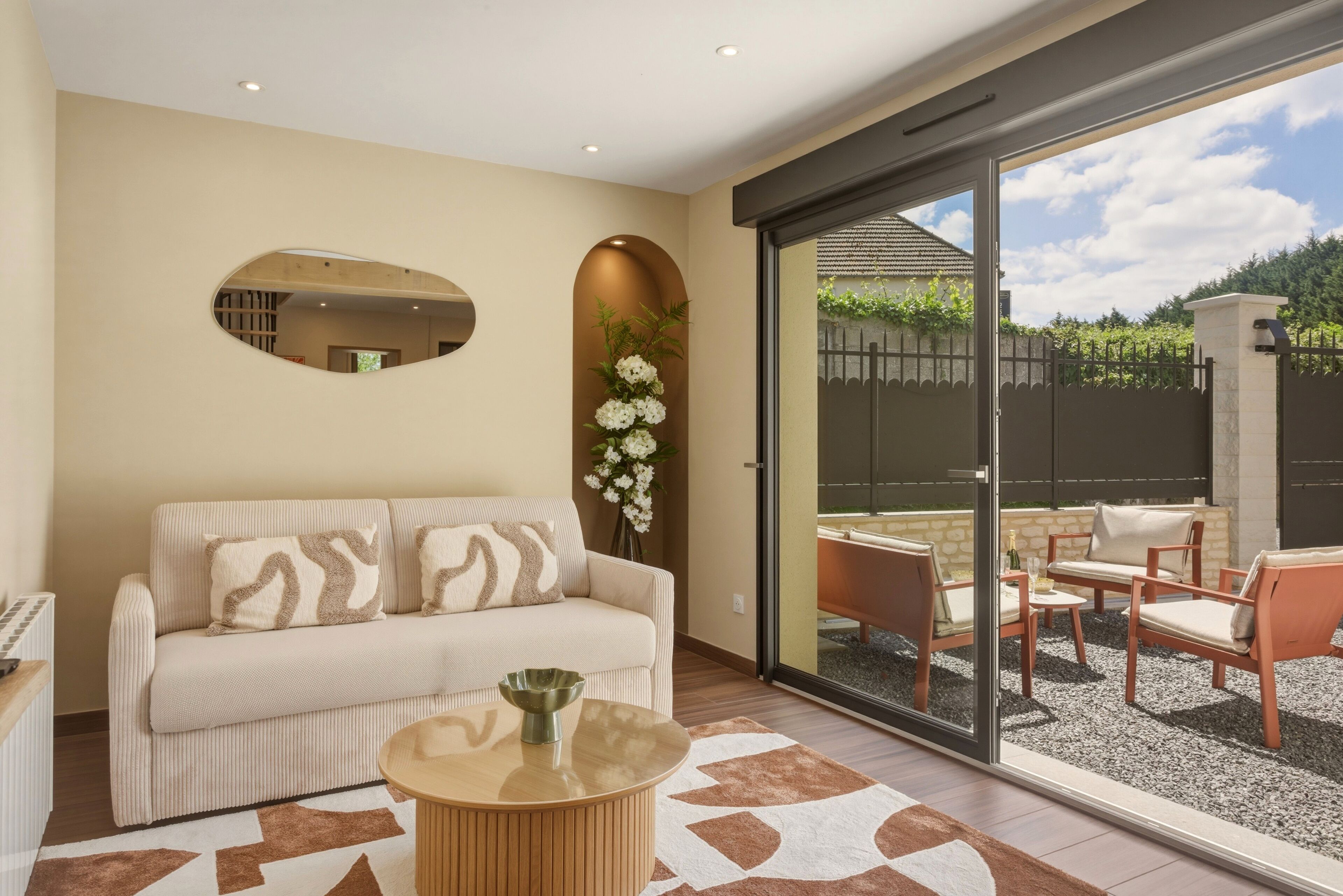 Un salon moderne avec un canapé, une table basse et un espace salon extérieur donnant sur un jardin.. ✨ La bohème - Élégante maison confidentielle