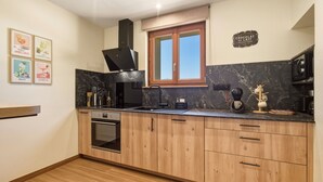 Eine moderne Küche mit Holdekor, einer schwarzen Arbeitsplatte, einem eingebauten Backofen und einem Fenster mit Ausblick.