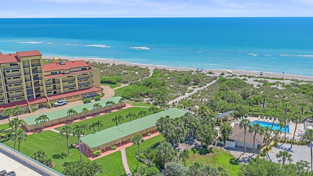 Un resort con piscina, cancha de tenis y vista al mar.