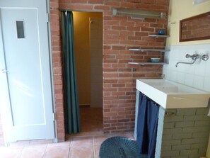 Ein Badezimmer mit einem weißen Waschbecken, einer Duschvorhang und einer Backsteinwand.