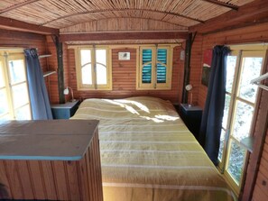 A wooden cabin room with a bed, two windows with shutters, a desk, and a chair. - Veyronne caravan (Aubres)