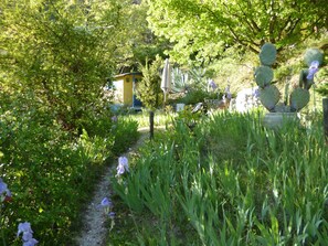 A garden path with greenery and cacti, a yellow building, and a fence. - Veyronne caravan (Aubres)