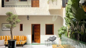 Une cour avec une piscine, un ensemble de canapés, un fauteuil et un arbre en pot.