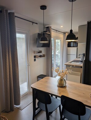 Eine moderne Küche mit Essbereich, ausgestattet mit einem Holztisch, schwarzen Stühlen und Pendelleuchten.
