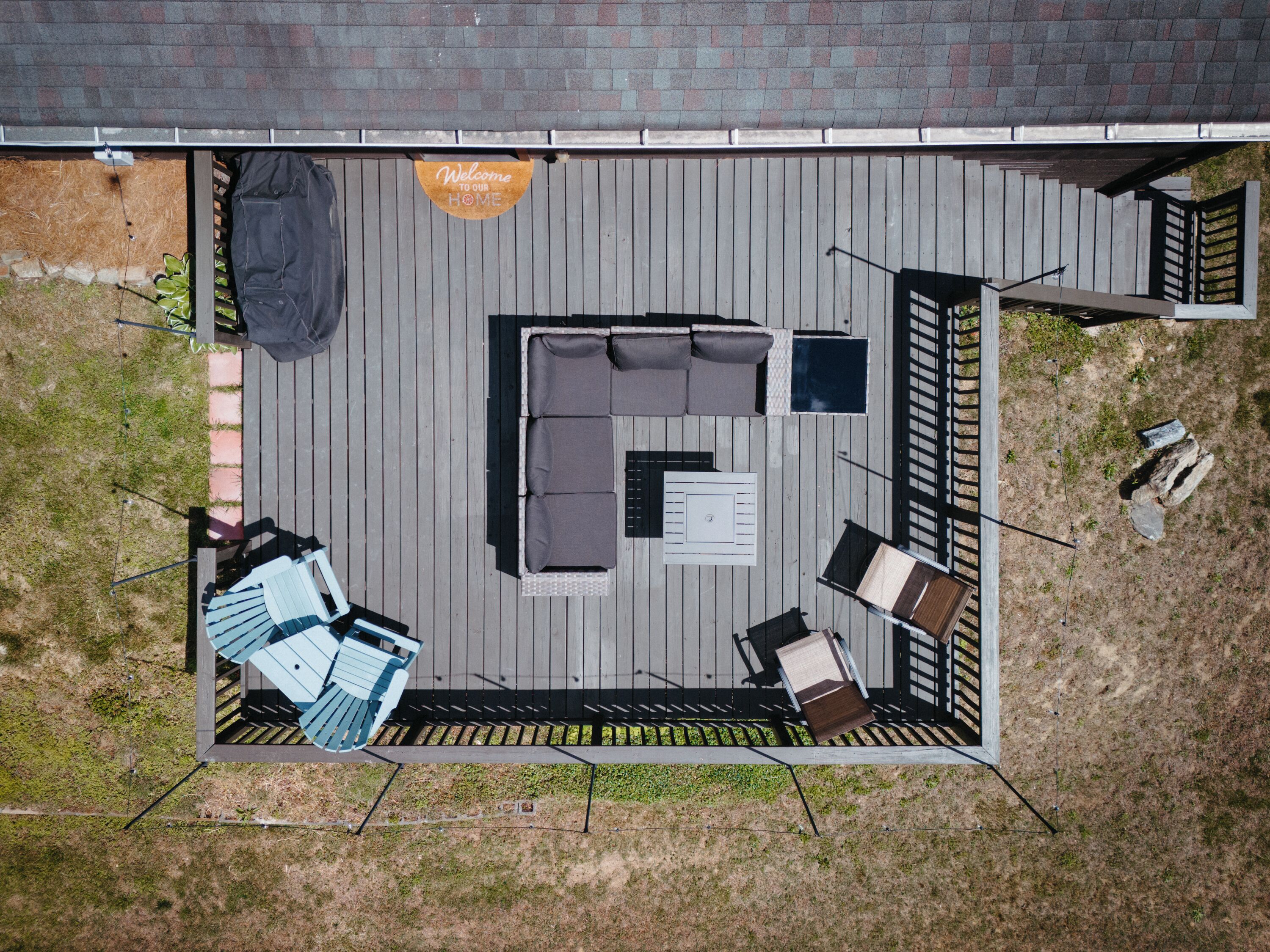 An outdoor patio with a sectional sofa, a small table, and a grill area.