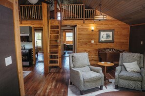 Ein Holzblockhaus-Innenraum mit Schlafzimmer auf dem Schlafboden, Essbereich und Küche.