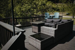 En terrasse med fletningsmøbler, herunder en sofa og stole, samt et lille bord.