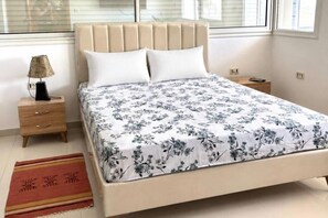 A bedroom with a bed, bedside tables, a lamp, and a window. - Spacious apartment with terrace near the beach (Bizerte)