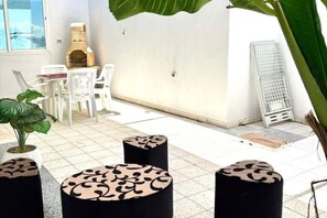 A patio area with a grill, white chairs, and round tables. - Spacious apartment with terrace near the beach (Bizerte)