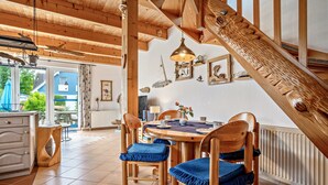 Un comedor de madera con una mesa, sillas, una lámpara colgante y una escalera.