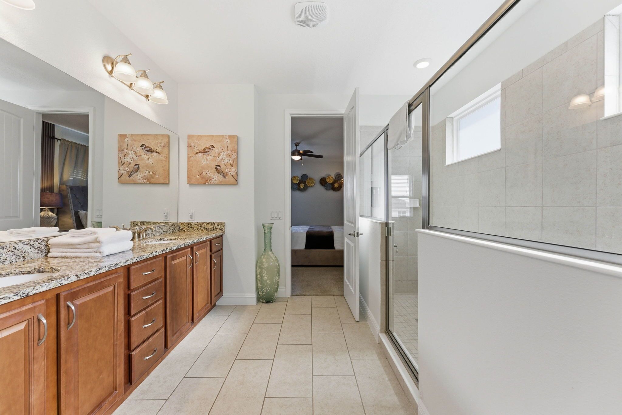 A modern kitchen with a granite countertop, wooden cabinets, and a large mirror.