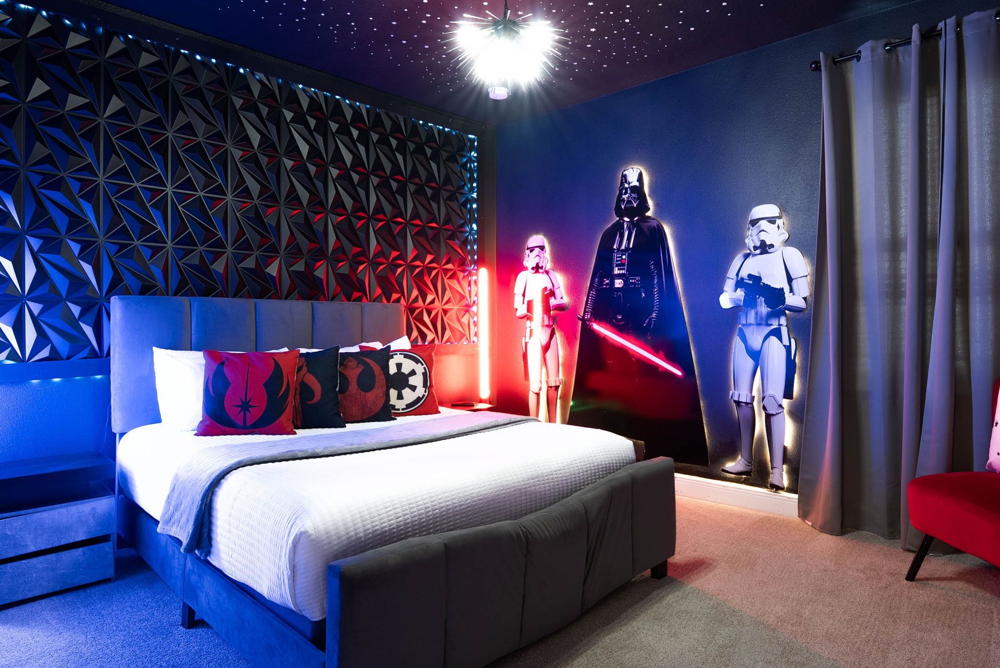 A bedroom with a Star Wars-themed wall, a bed with a geometric headboard, and a red chair.