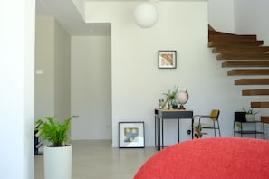 A modern interior with a staircase, a potted plant, and framed artwork on the wall.