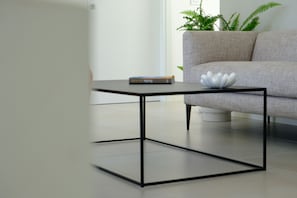 A modern living room with a minimalist coffee table, a sofa, and a potted plant.