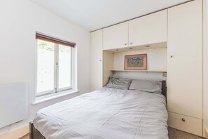 Ein Schlafzimmer mit Bett, Fenster, Heizkörper und Schrank.