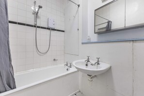 Ein Badezimmer mit einer weißen Badewanne, einem Waschbecken und einer Duschbrause.