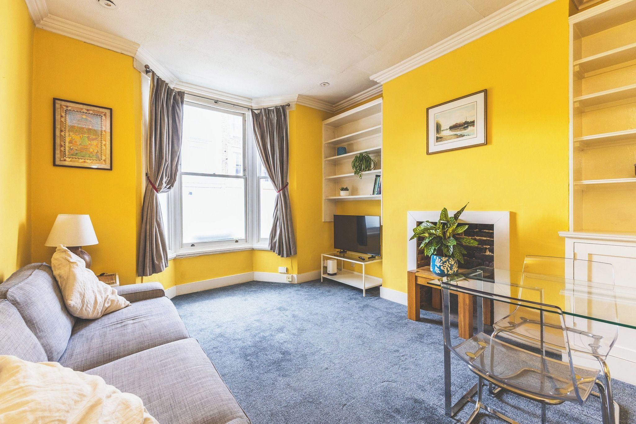 A living room with a sofa, a TV, a glass table, and a bookshelf.