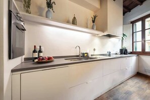 Une cuisine équipée d’un four encastré, d’un évier et d’une fenêtre.