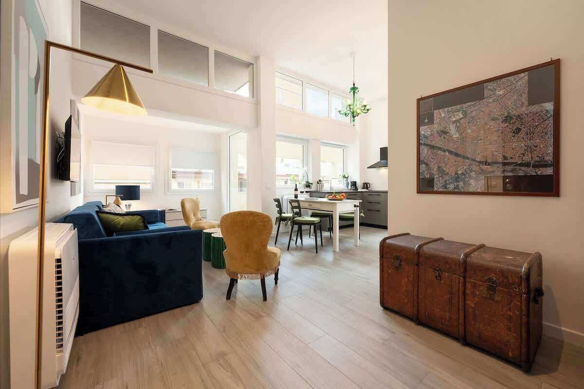 A spacious living area with a sofa, armchair, dining table, and a vintage trunk.