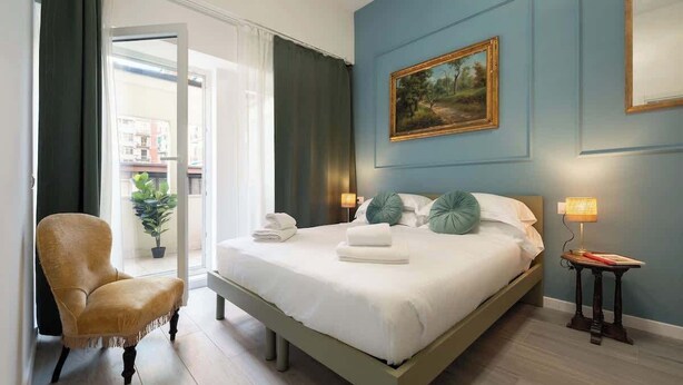 Ein Schlafzimmer mit einem Bett, einem Sessel, einem Nachttisch und einem Bild an der Wand.