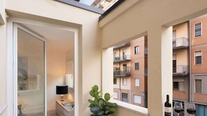 Ein kleiner Balkon mit einem Blumentopf, einem Tisch und einer Weinflasche.